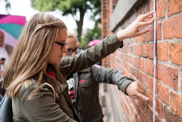 Schülerinnen beim Bearbeiten einer MathCityMap Aufgabe durch Zählen und Messen von Backsteinen in Kappeln.