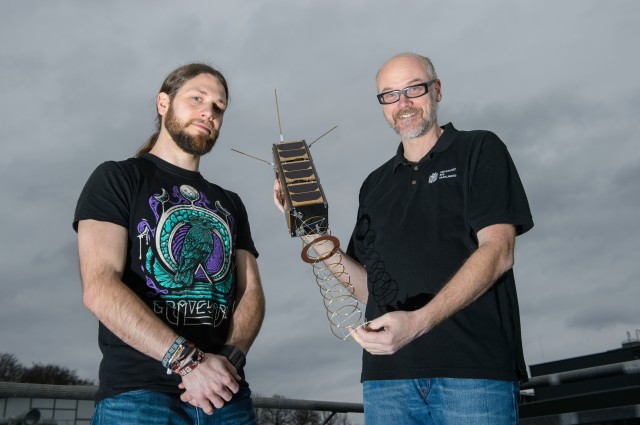 Gilles Nies und sein Doktorvater Holger Hermanns mit dem Satelliten, dessen Mission sie mit neuen Rechenmodellen absichern.